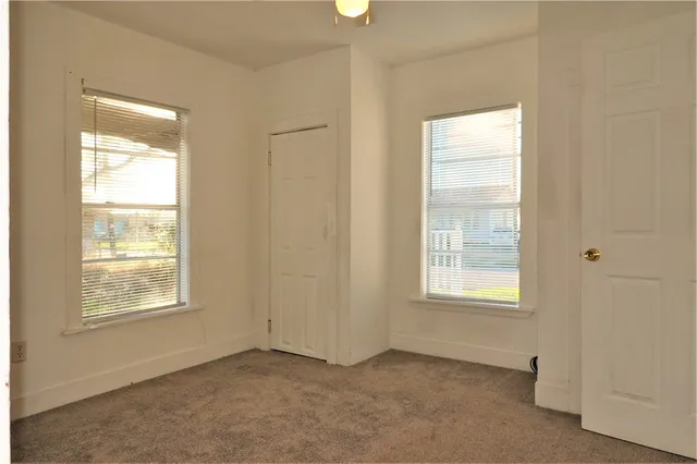 an empty room with windows and cabinet