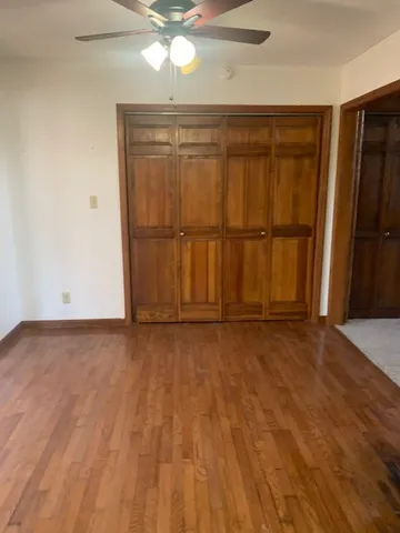an empty room with wooden floor and fan