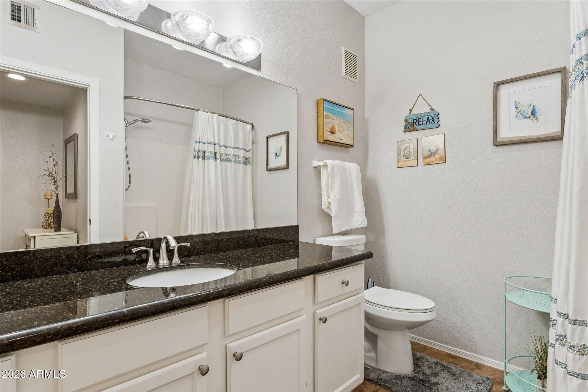 10030 West Indian School Road, Unit 269 Phoenix, AZ 85037 - Photo 16 of 29 a bathroom with a granite countertop sink mirror vanity and toilet