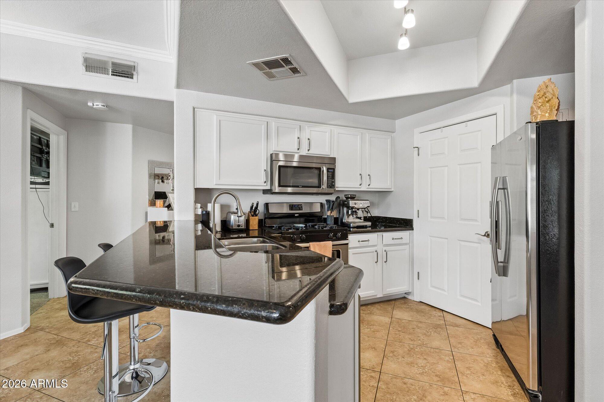 10030 West Indian School Road, Unit 269 Phoenix, AZ 85037 - Photo 2 of 29 a kitchen with kitchen island a counter top space cabinets and stainless steel appliances