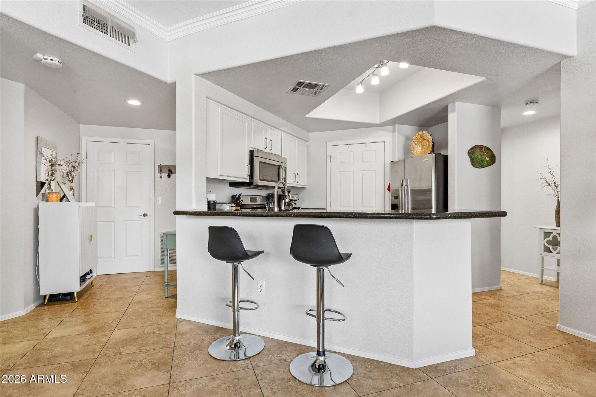 10030 West Indian School Road, Unit 269 Phoenix, AZ 85037 - Photo 3 of 29 a kitchen with cabinets and chairs