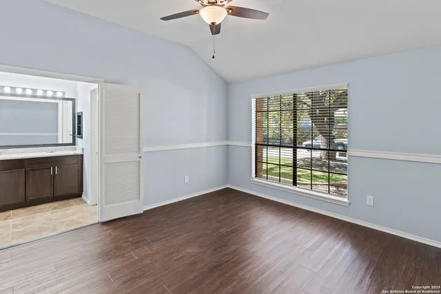 a view of an empty room with a window and wooden floor