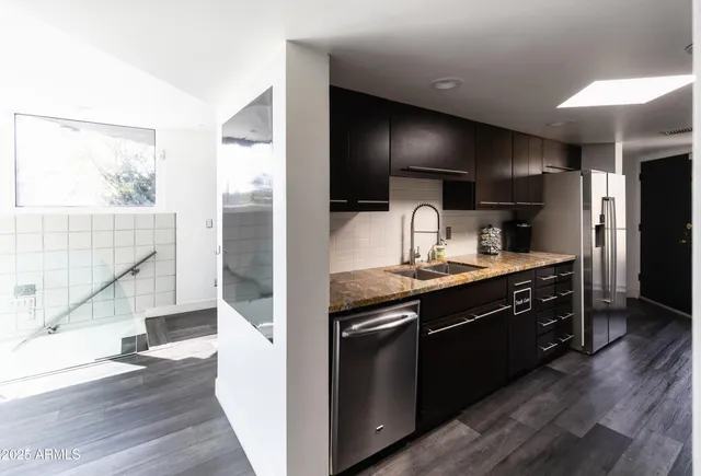 a kitchen with granite countertop a sink a counter space cabinets and stainless steel appliances