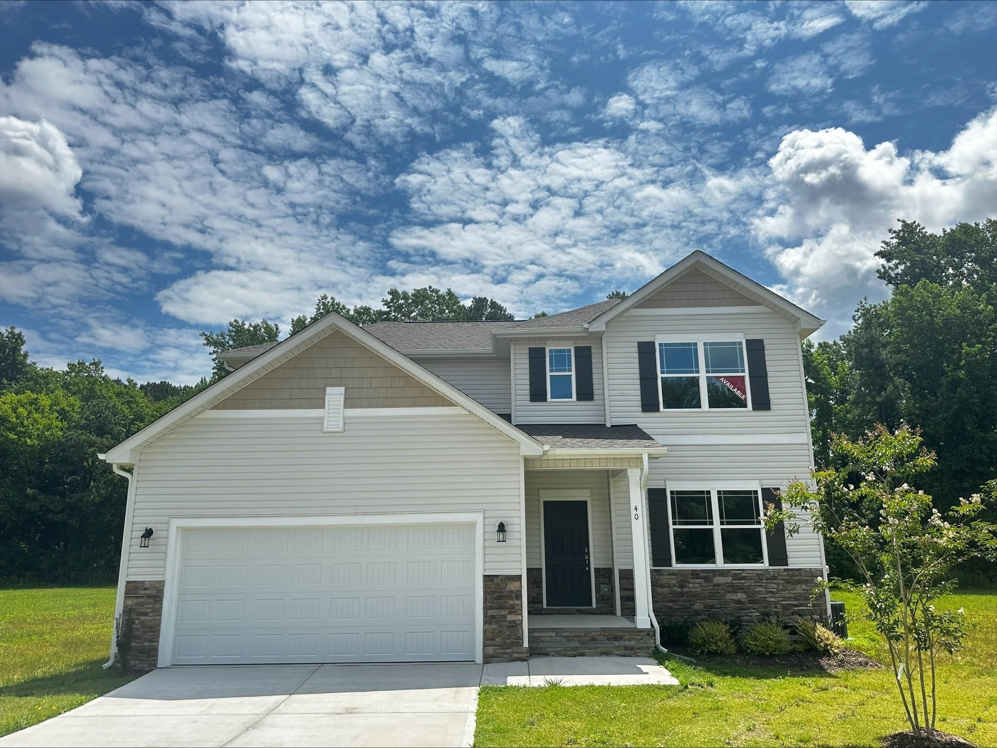 a white house with a small yard and trees in the background