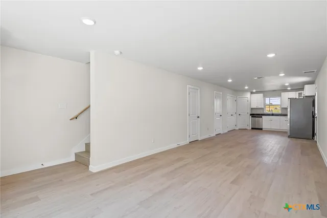 an empty room with wooden floor and appliances