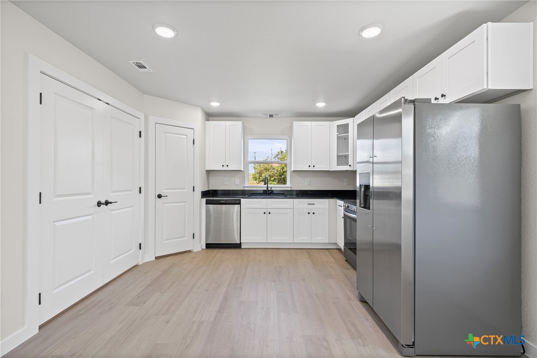 1407 South 5th Street Temple, TX 76504 - Photo 13 of 33 a kitchen with stainless steel appliances granite countertop a refrigerator sink and white cabinets