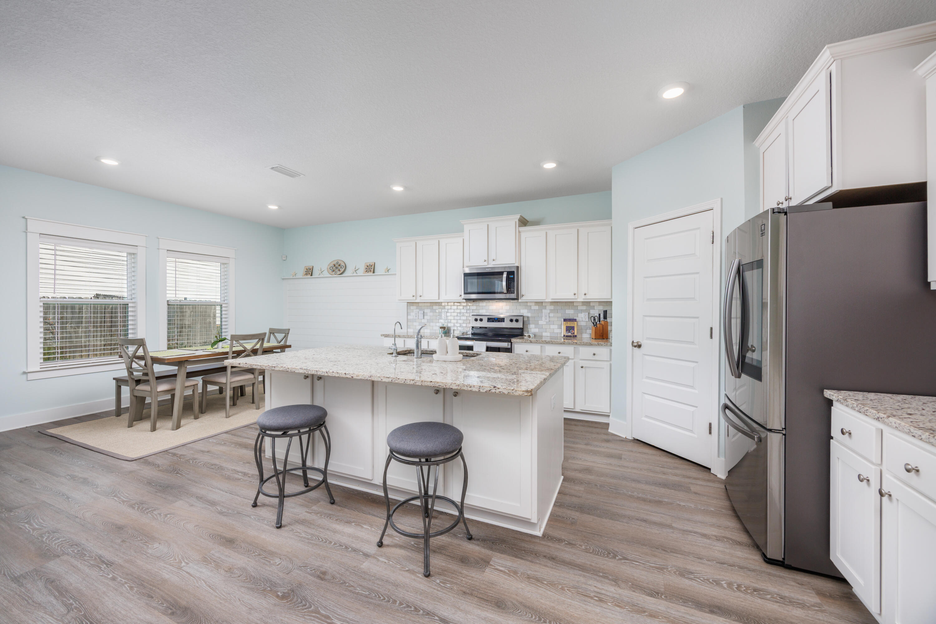 193 Perimeter Place Freeport, FL 32439 - Photo 11 of 43 a kitchen with stainless steel appliances a refrigerator a stove a sink a dining table and chairs with wooden floor