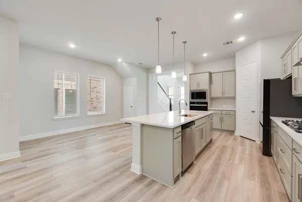 a large kitchen with stainless steel appliances kitchen island a large counter top and a wooden floor