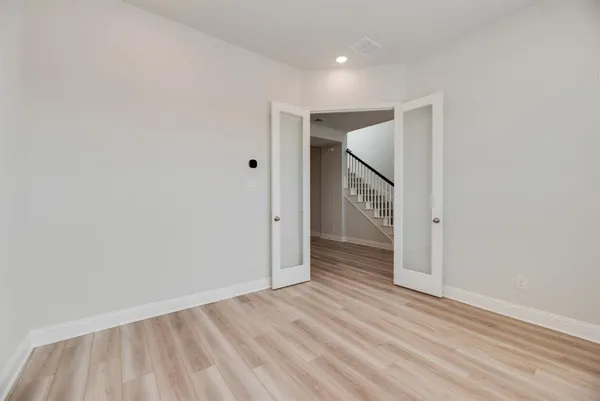 a view of an empty room with closet and wooden floor