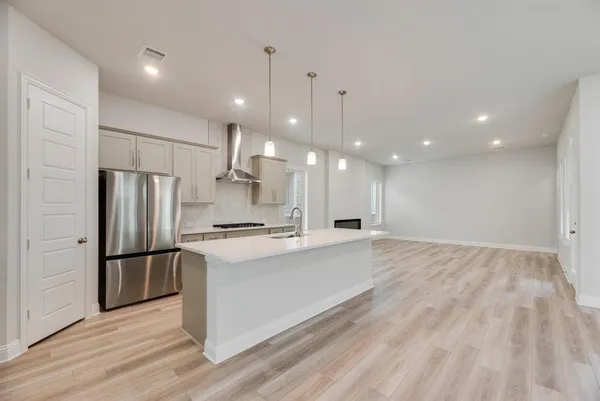 a large kitchen with kitchen island a stove a refrigerator a sink and a oven with wooden floor