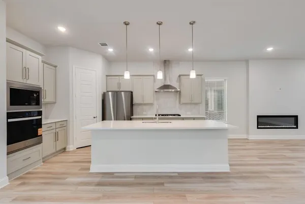 a large kitchen with stainless steel appliances kitchen island a large counter top and a wooden floors