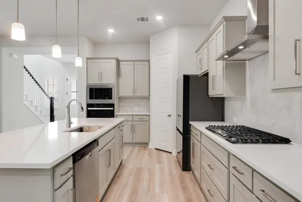 a kitchen with a sink stainless steel appliances a counter space and cabinets