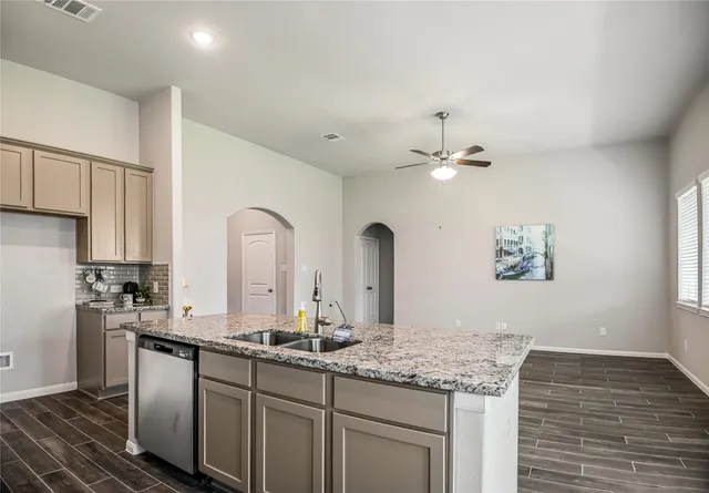 a kitchen with stainless steel appliances granite countertop a stove top oven a sink a refrigerator white cabinets and wooden floor