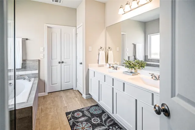 a bathroom with a double vanity sink a mirror and a bathtub