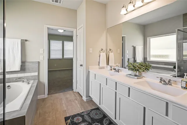 a bathroom with a tub sink shower and mirror