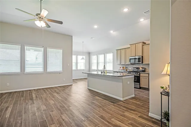 a kitchen with granite countertop a stove top oven a sink dishwasher and a microwave oven with wooden floor