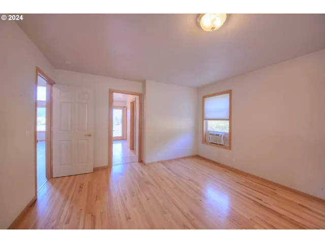 a view of an empty room and window with wooden floor