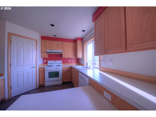 a kitchen with stainless steel appliances a sink cabinets and a wooden floor