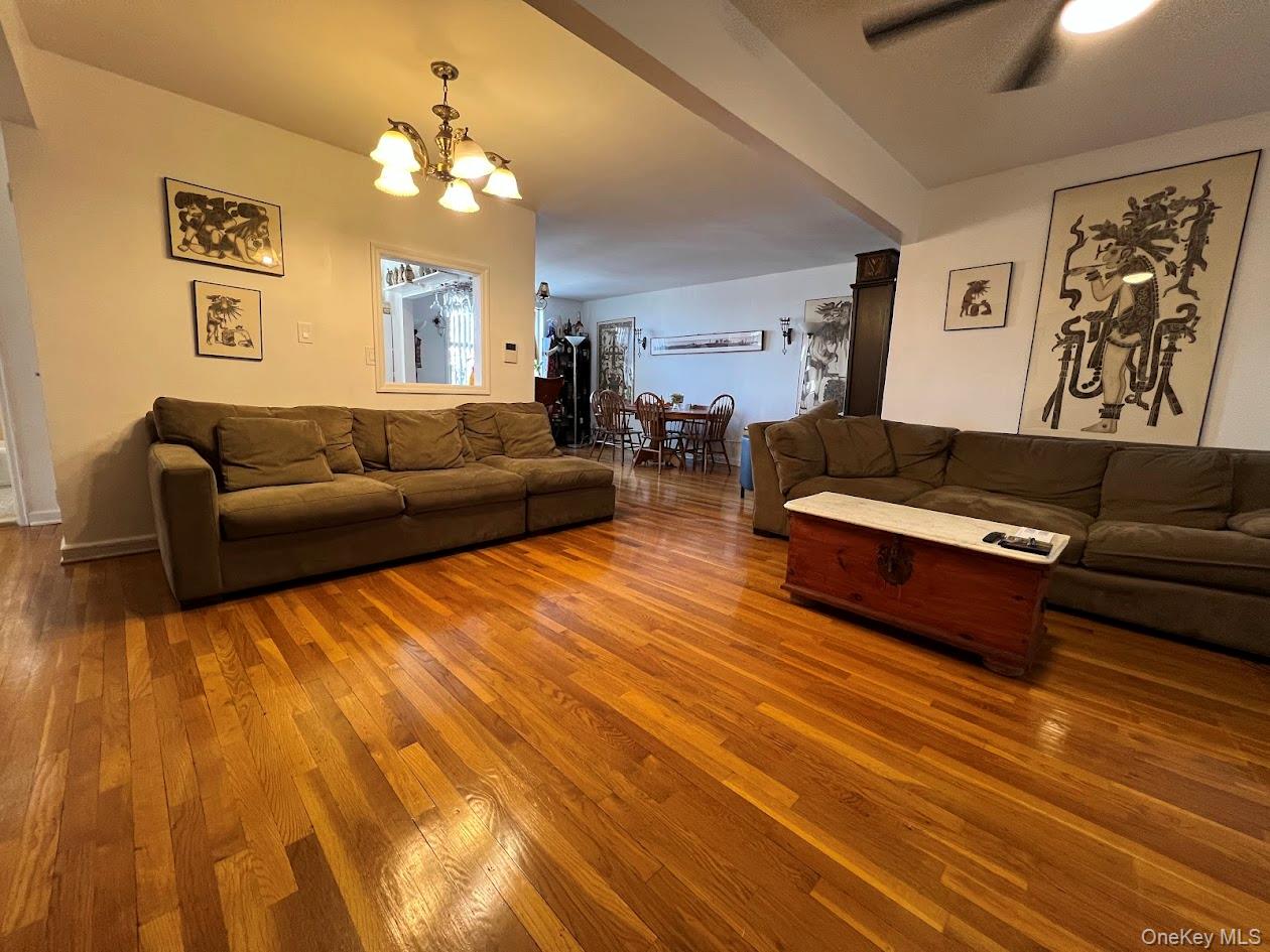 Living area with ceiling fan with notable chandelier and hardwood / wood-style flooring