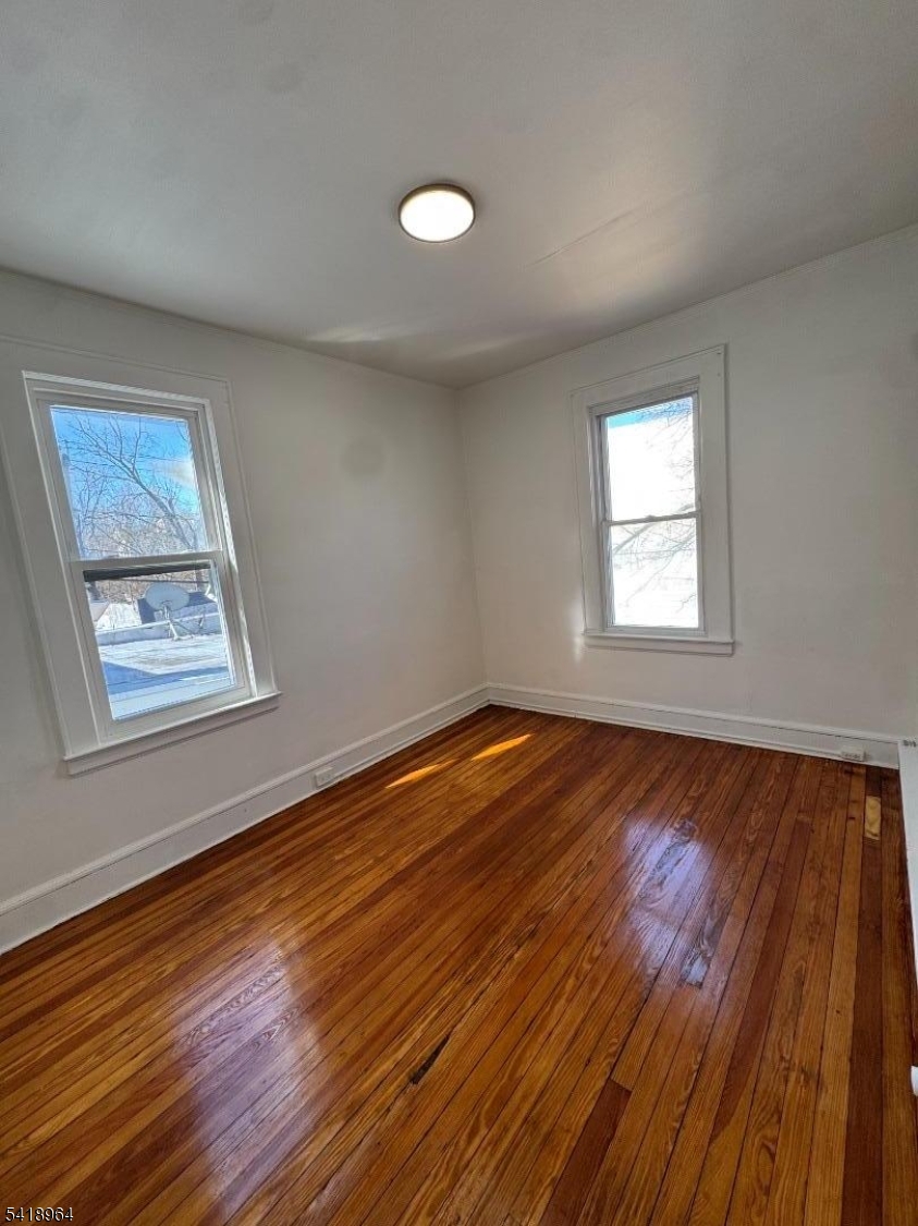 149 Brookside Avenue, Unit 2 Irvington, NJ 07111 - Photo 2 of 8 a view of an empty room with wooden floor and a window