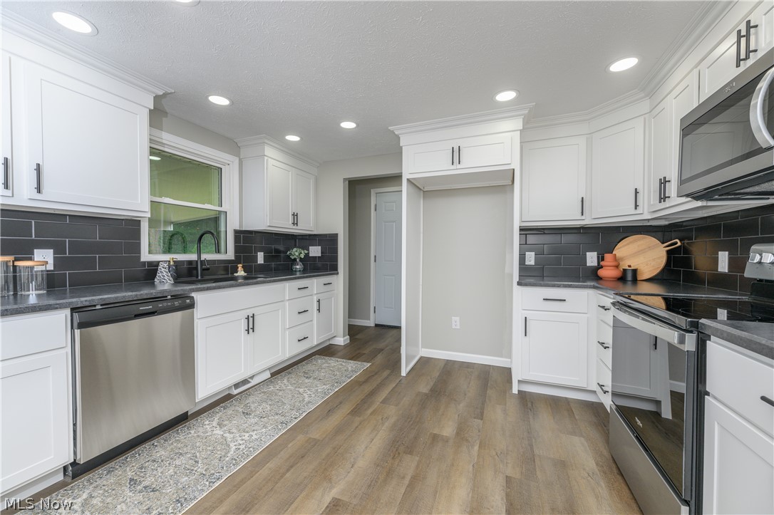 4855 4th Street Northwest Canton, OH 44708 - Photo 5 of 25 Kitchen with sink, appliances with stainless steel finishes, wood-type flooring, and backsplash