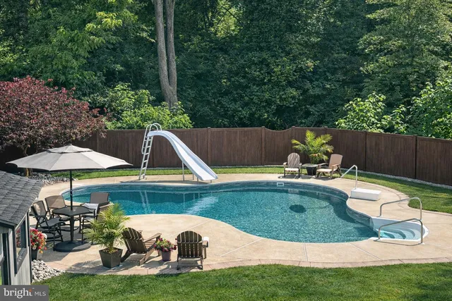 a view of a table and chairs under an umbrella in backyard