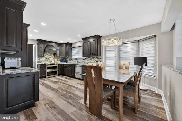 a kitchen with stainless steel appliances kitchen island granite countertop a table chairs and a refrigerator