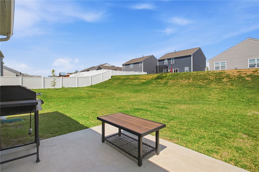 216 Boxbury Way Fountain Inn, SC 29644 - Photo 23 of 28 An open concrete patio looks out over a grassy yard enclosed by vinyl fencing.