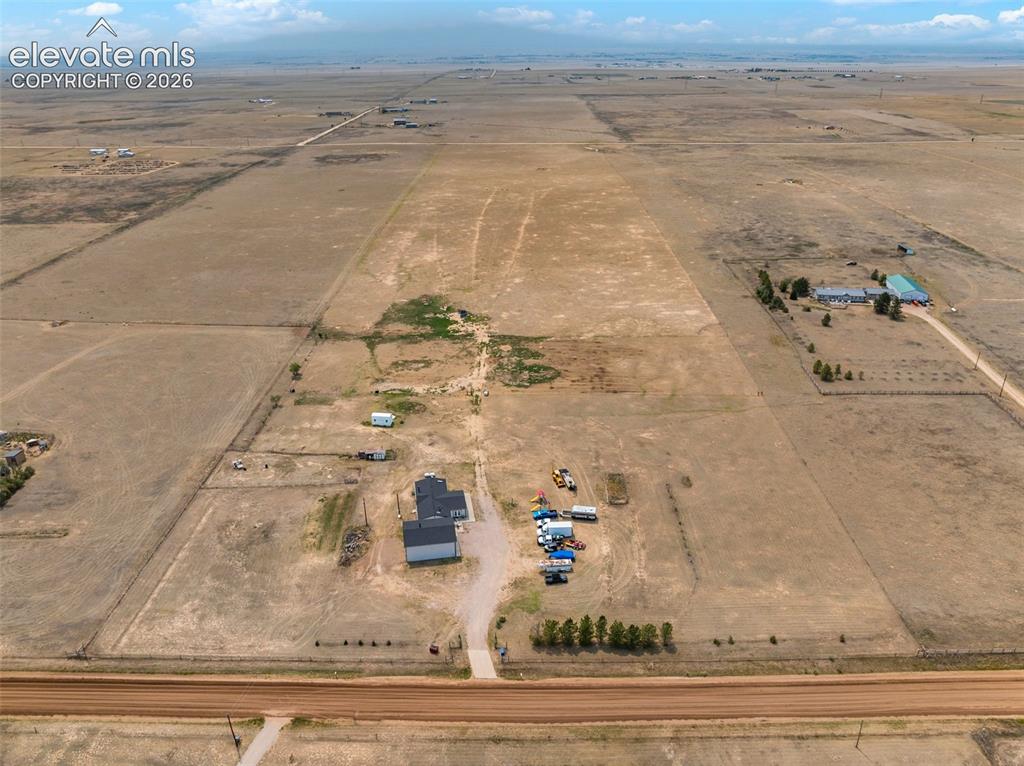 1350 South Calhan Highway Yoder, CO 80864 - Photo 44 of 45 Expansive rural property featuring a newly constructed residence with a dark gray roof and light gray siding, a separate detached structure, and a long gravel driveway