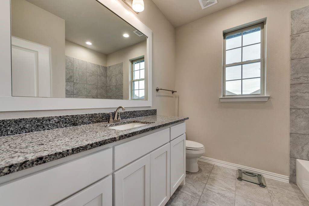 125 Katalina Lane Waxahachie, TX 75165 - Photo 28 of 34 a bathroom with a granite countertop sink a toilet and a window