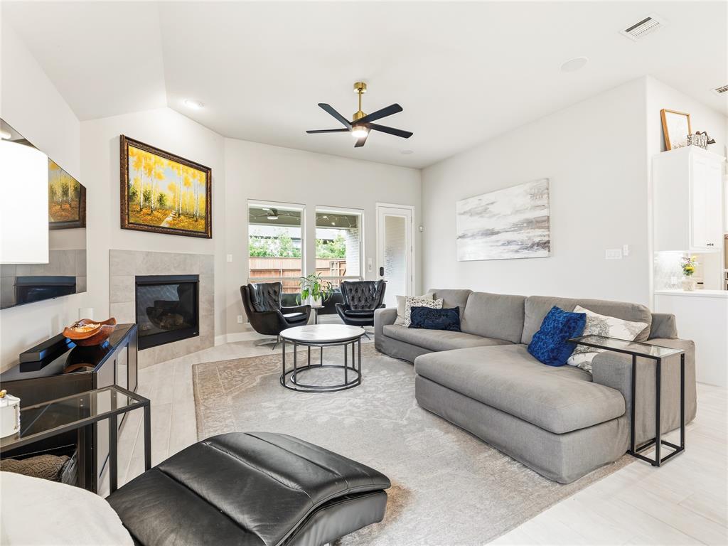 15340 Crape Myrtle Road Frisco, TX 75035 - Photo 15 of 40 Spacious living area featuring a vaulted ceiling, light wood-finish flooring, a contemporary ceiling fan, and a fireplace with a light-toned tile surround