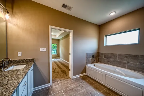 a bathroom with a granite countertop tub sink and mirror