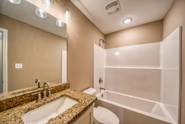 a bathroom with a granite countertop sink a toilet and bathtub
