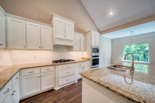 a kitchen with granite countertop a stove sink and cabinets
