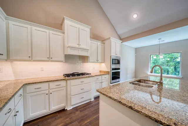 a kitchen with granite countertop a stove sink and cabinets