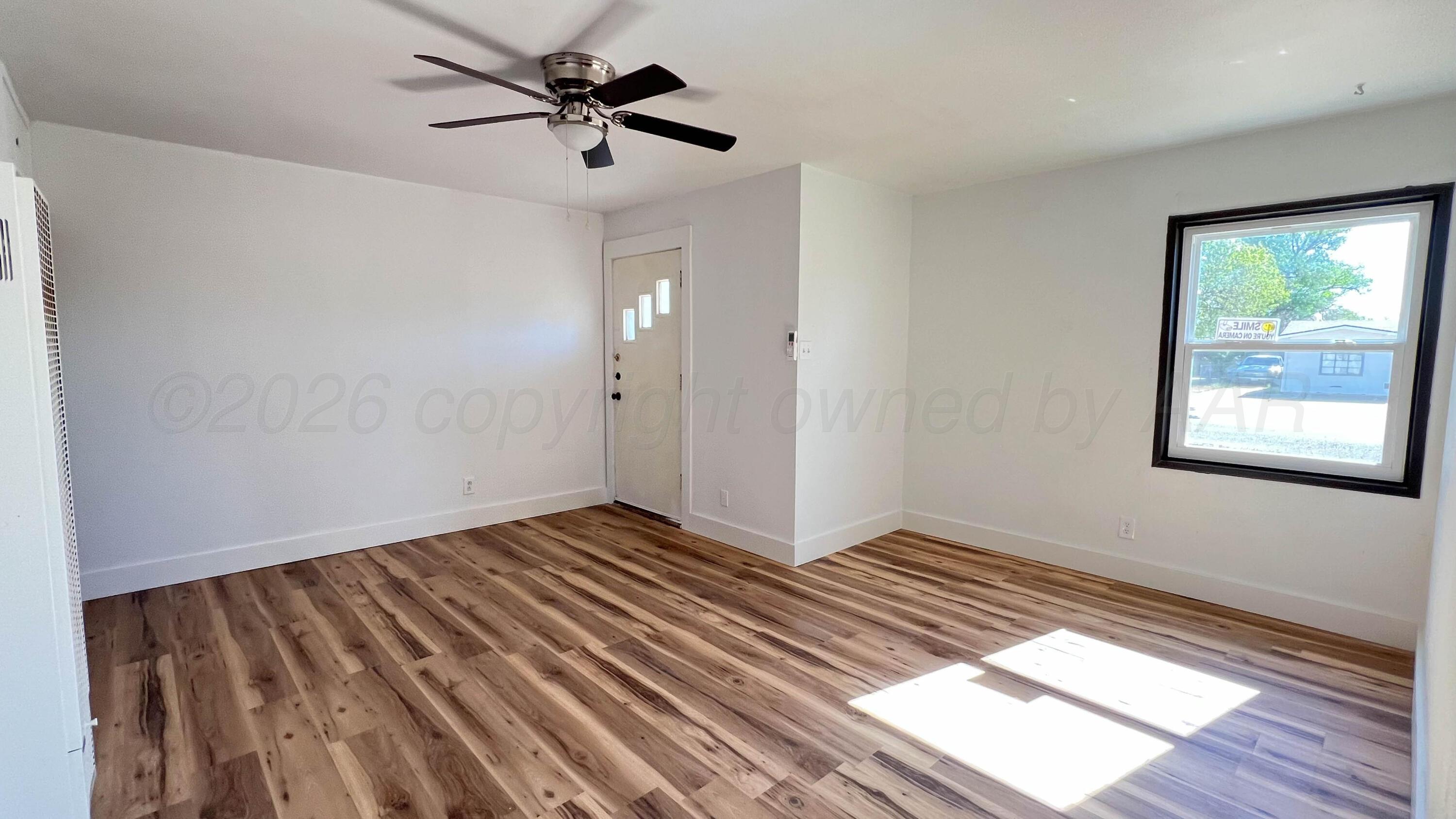4410 South Ong Street Amarillo, TX 79110 - Photo 3 of 22 a view of an empty room with window and wooden floor