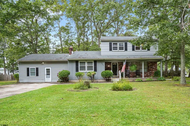 a front view of a house with garden and trees