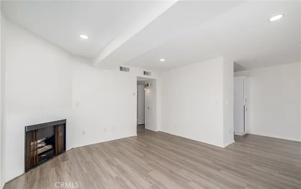 a view of an empty room with wooden floor and a fireplace