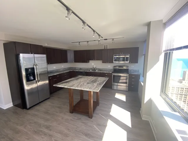 a open kitchen with stainless steel appliances granite countertop a stove and a refrigerator