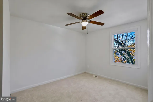 an empty room with wooden floor and ceiling fan
