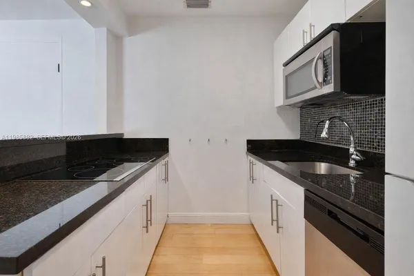 a kitchen with granite countertop a sink dishwasher stove and cabinets