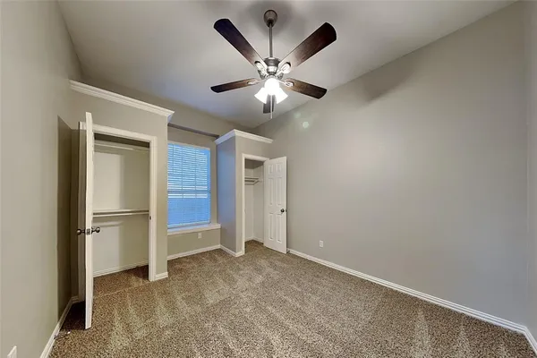 an empty room with closet and a ceiling fan