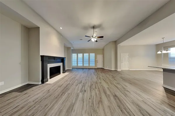 an empty room with wooden floor fireplace and windows