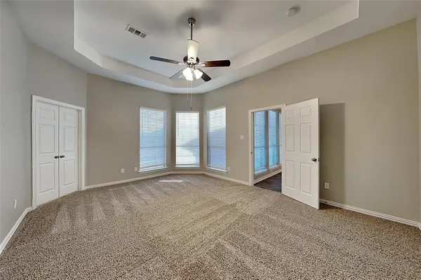 an empty room with chandelier fan and windows