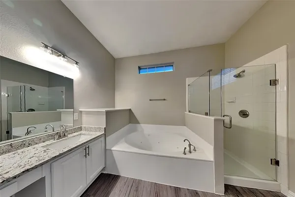 a bathroom with a granite countertop tub sink shower and mirror