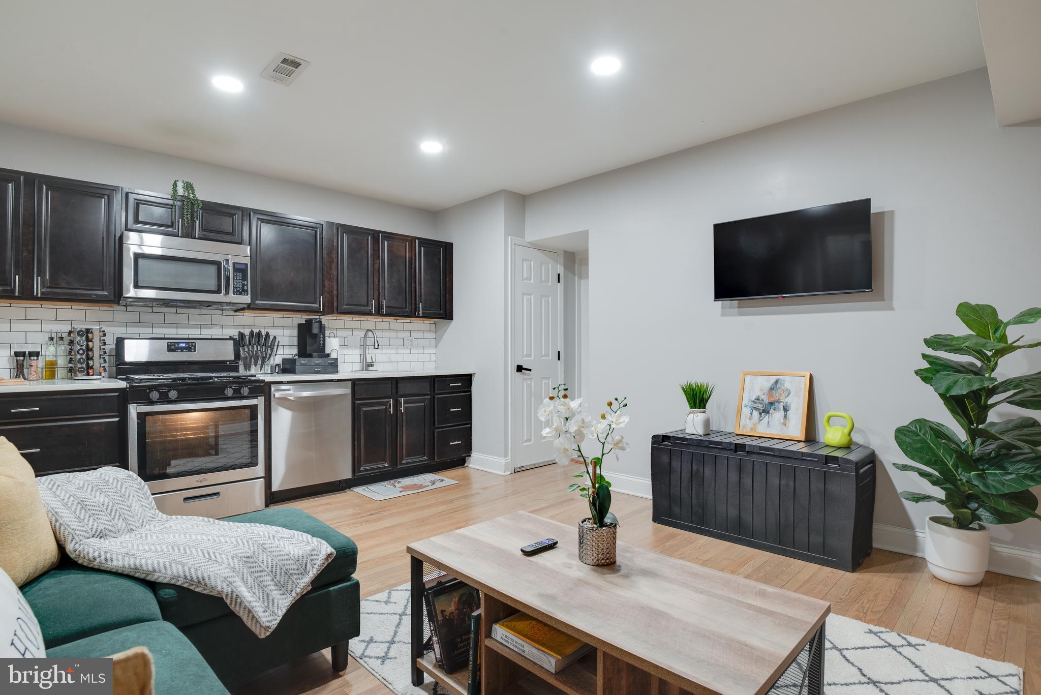 1255 Raum Street Northeast, Unit 1 Washington, DC 20002 - Photo 5 of 31 a kitchen with stainless steel appliances a stove a sink a microwave a dining table and chairs