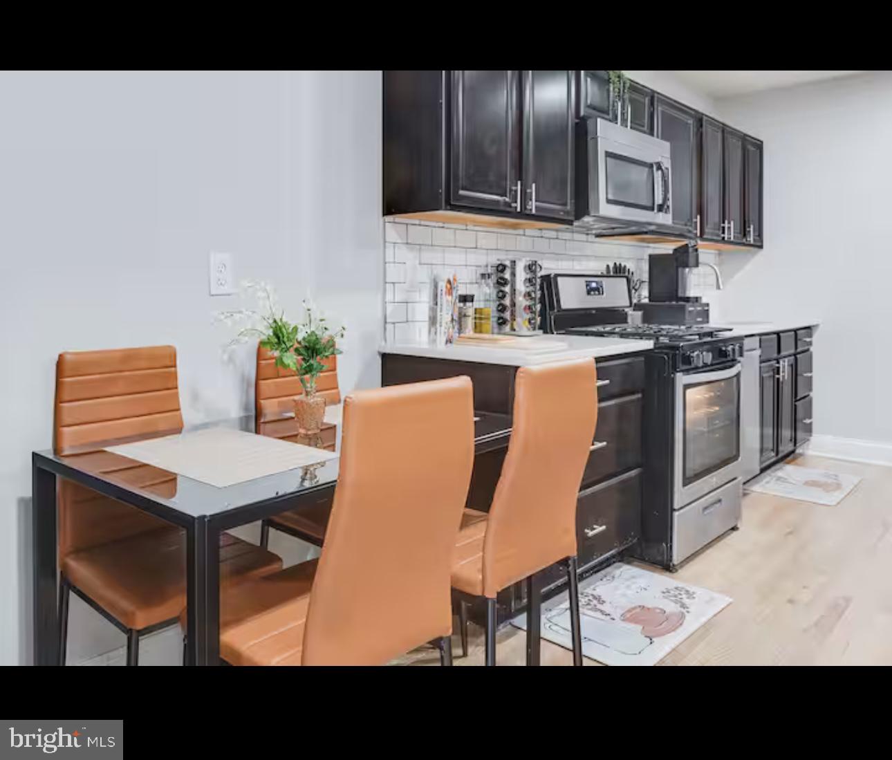 1255 Raum Street Northeast, Unit 1 Washington, DC 20002 - Photo 7 of 16 a kitchen with stainless steel appliances kitchen island granite countertop a table chairs and a microwave