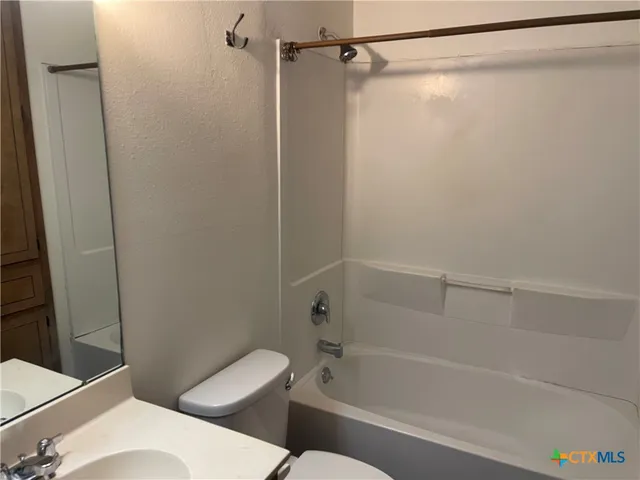 a white toilet and tub sitting next to a bathroom sink