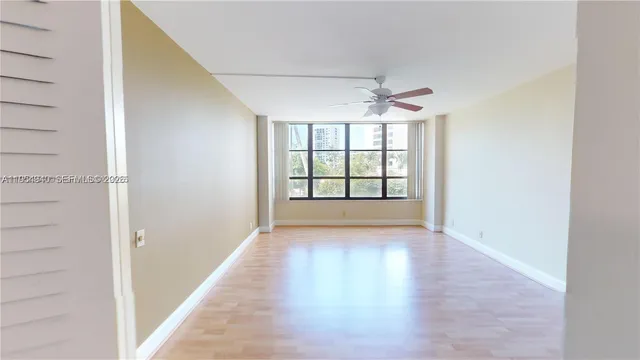 an empty room with windows and chandelier fan