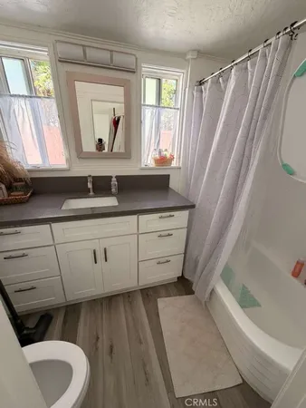 a bathroom with a granite countertop sink vanity mirror bathtub and toilet